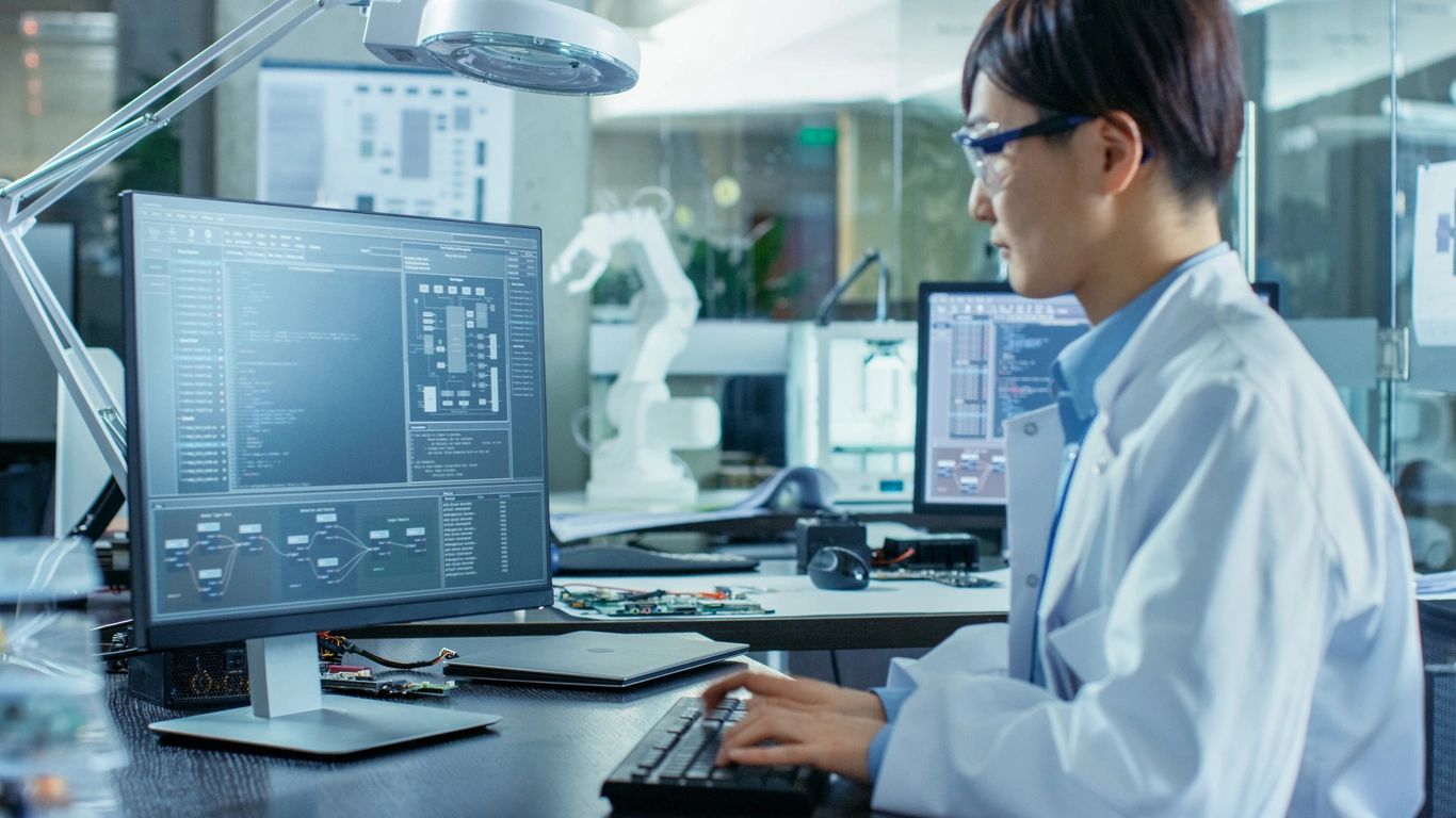 A person sitting at a desk with two computers.