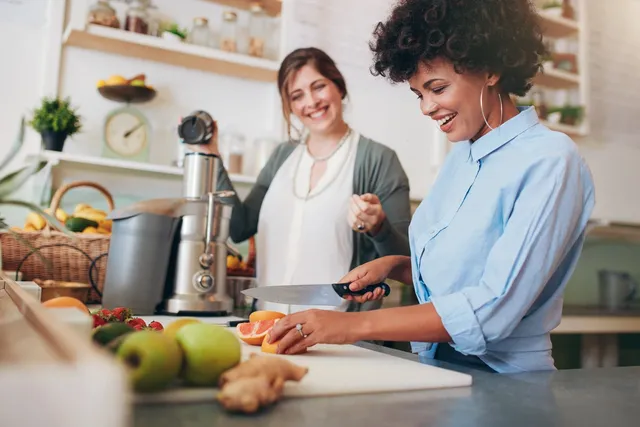 Two women are preparing food in a kitchen.